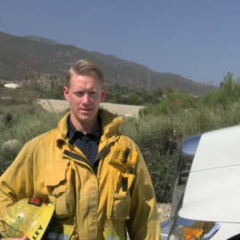 Wildland Firefighter standing next to the fire engine at the foothills of the mountain to provide a public service announcement