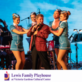 Man singing in a red suit surrounded by four stewardess